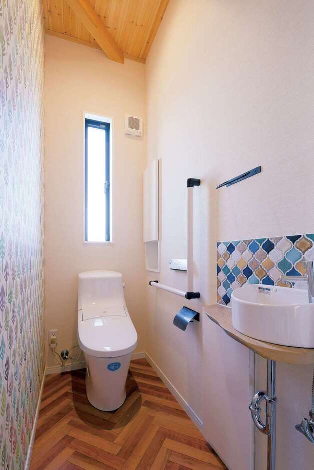 ヘリンボーン柄の床と手洗いのタイルがオシャレな1階のトイレ