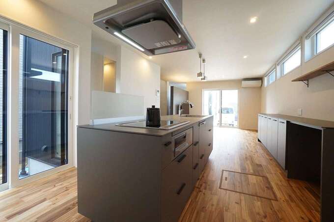 回遊性の高いアイランドキッチンは奥さまからのリクエスト。シャープなデザインのキッチンは『R＋house』オリジナルで、8mmの薄い天板とサイドパネルの美しいフォルムが空間にマッチしている。向かいの窓越しにはシンボルツリーが見える