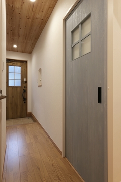 木製の天井と床が温かみを感じさせる廊下。ドアのペイント仕上げがアクセントとなり、開放感のある落ち着いた空間となっている。