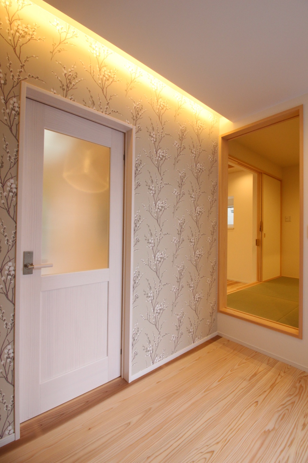 小野田産業～designers house project～｜温かみのある照明が印象的な廊下。壁紙は自然を感じさせるデザインで、落ち着いた雰囲気を演出している。