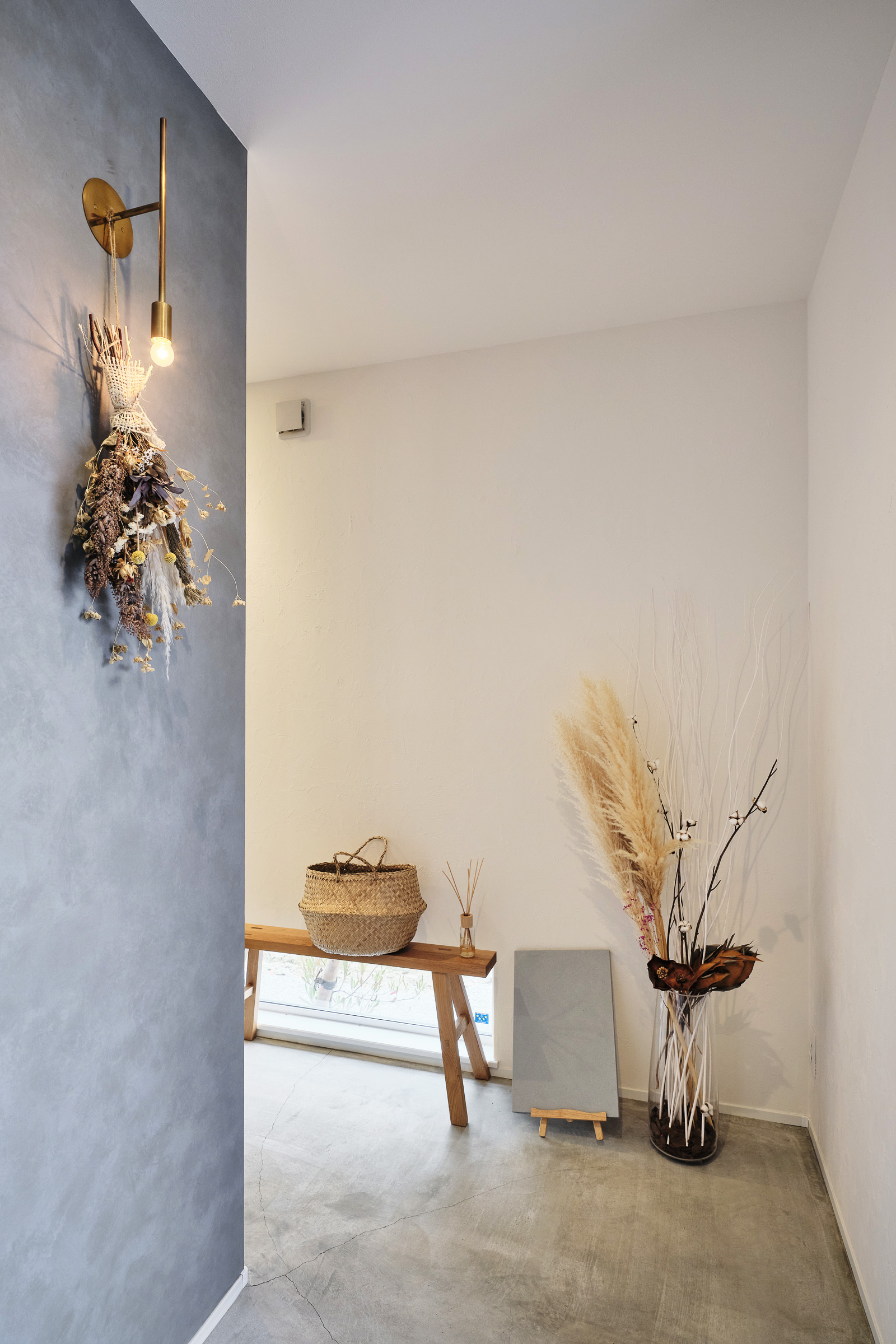 平屋建築ブルーハウス【ペット、建築家、平屋】リビングへ続くルートは主にゲスト用。アクセントカラーのグレーの壁紙にドライフラワーや小物を添えて、シャビーシックにコーディネート。玄関と居住空間の段差をなくしたバリアフリー仕様で愛犬にもやさしい