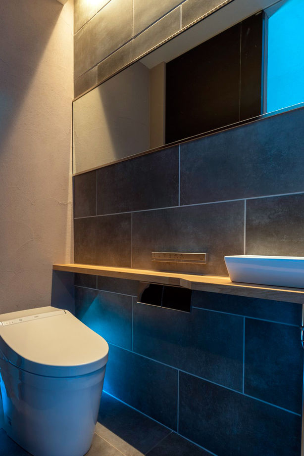 チェックハウス｜ラグジュアリーなトイレ空間。シックな壁面と間接照明が融合し、洗練された落ち着きを感じさせるデザインとなっている。