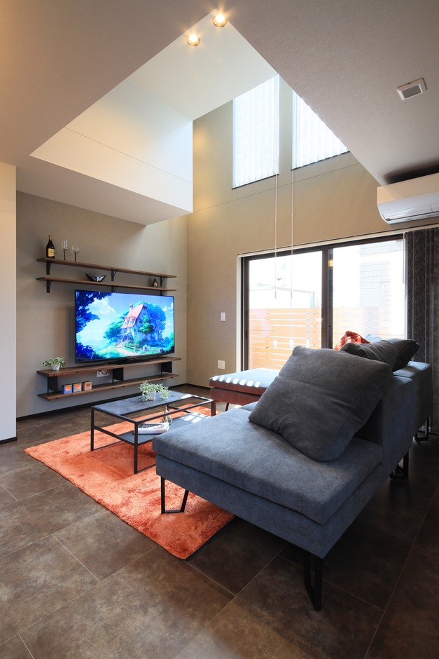 高い天井と大きな窓が特徴のリビング空間。広々としたソファが置かれ、家族でくつろぐのに最適な場所となっている。