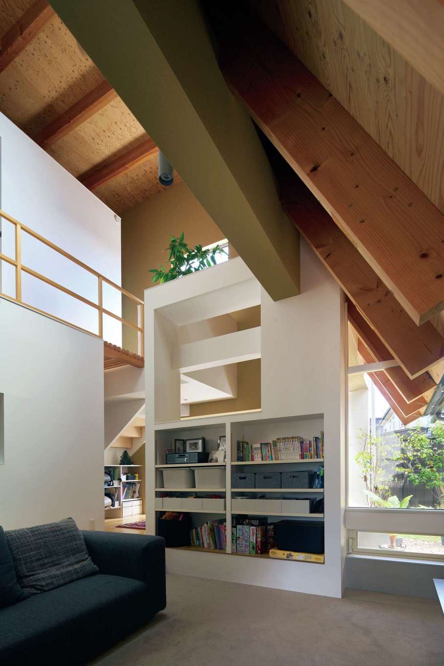 MABUCHI【デザイン住宅、間取り、建築家】スギの梁を現しにした吹抜けの大空間。リビングをフロアダウンしたことで、いっそう開放的に。所々で視線が奥へと抜ける壁が、リビングとダイニングをゆるやかにゾーニングしている