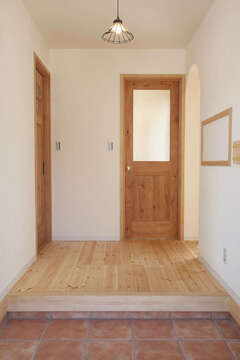 木の風合いを活かしたシンプル＆ナチュラルな雰囲気が、家族を温かく迎える玄関。正面のドアの先にはLDK、右手のR型の出入り口の奥はユーティリティスペース、左手のドアの先はトイレ