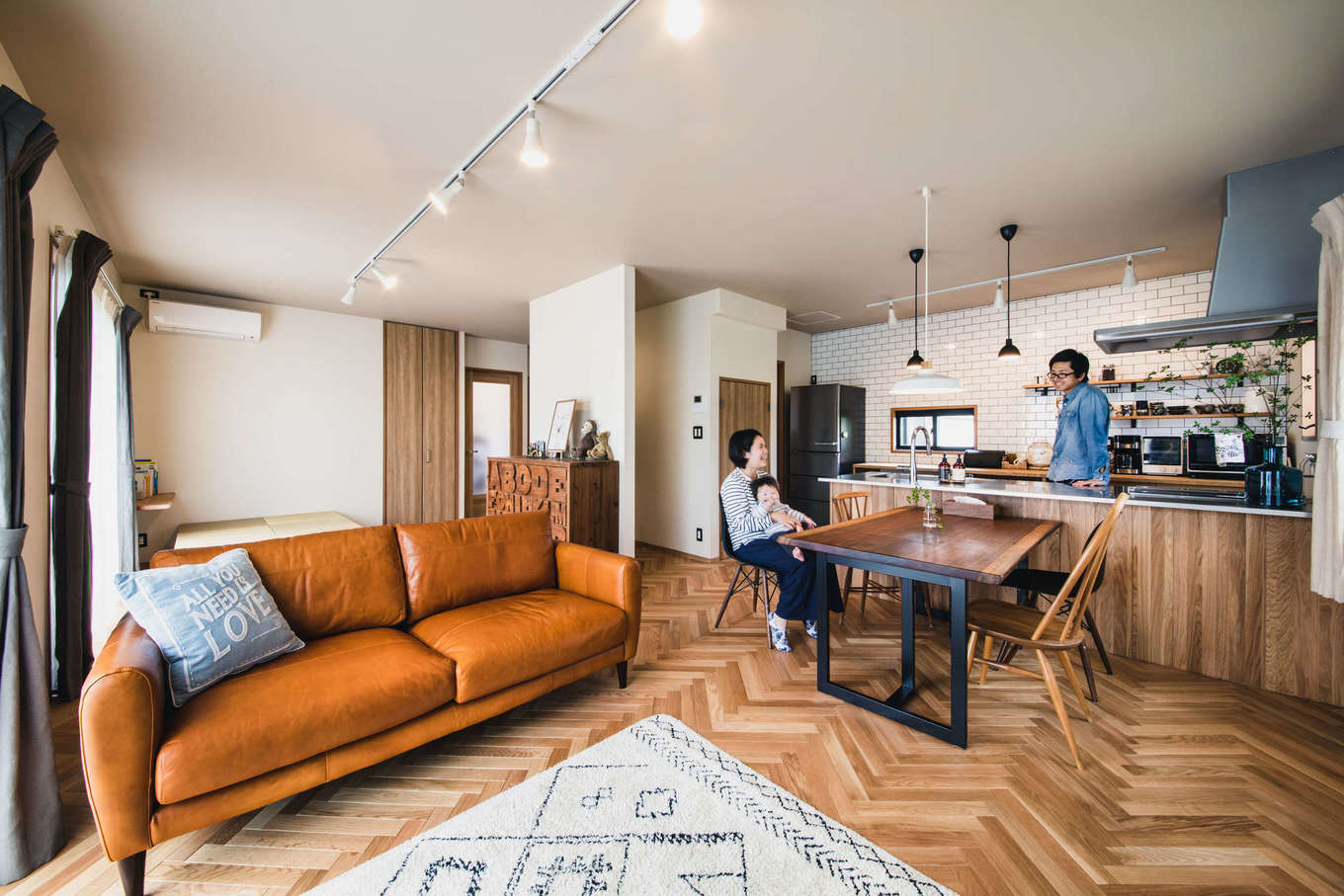 ALAIN（アラン）｜構造上問題のない非耐力壁を取り払い、キッチンからリビング、ダイニング、庭まで見渡せるように生まれ変わったLDK。無垢フローロングのヘリンボーン張りは、ベテランの大工が二人がかりで、8日間かけて美しく仕上げた。壁は漆喰と同じような質感で、水拭きメンテナンスが可能な英国製のFARROW & BALL（ファローアンドボール）を使用