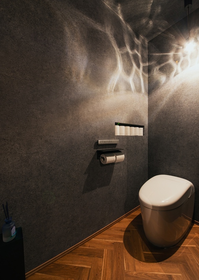 トイレもホテルライクなデザインに。グレージュの壁に照明が美しく反映し、リラックスできる。ヘリンボーン柄の床もおしゃれ