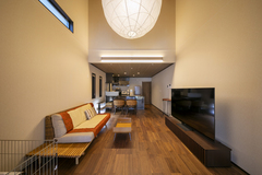 吹き抜けの縦長効果を感じる大空間のLDK。大きな照明と開放感のある天井が、空間に広がりをもたらしています。