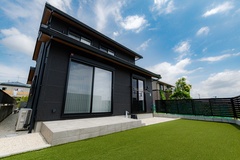 シンプルかつモダンなデザインの外観。広い庭に面した大きな窓が印象的で、自然光が室内に差し込む。