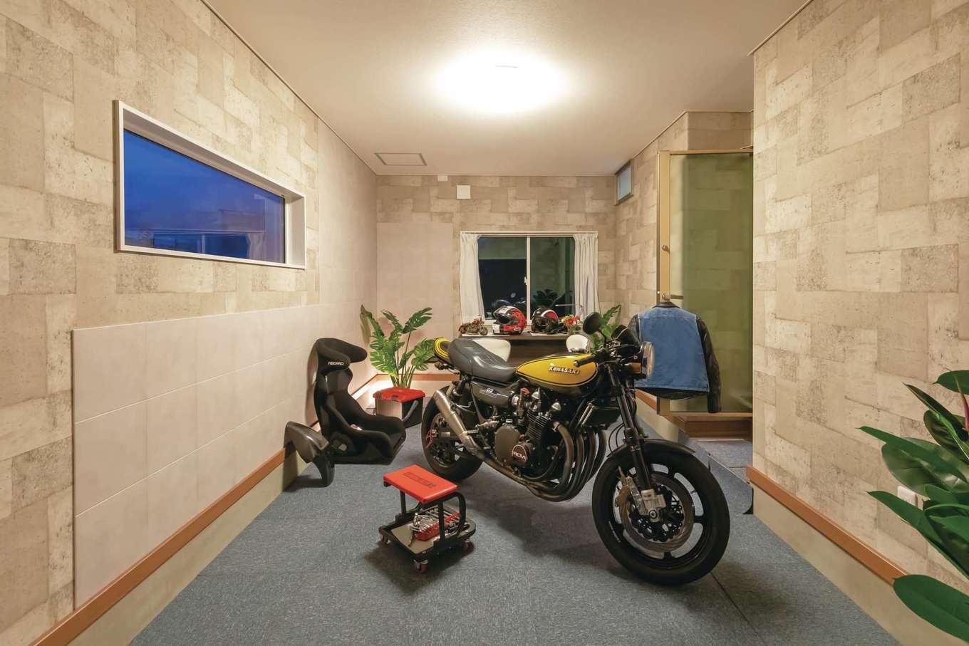 住宅工房 アリアンス【デザイン住宅、二世帯住宅、ガレージ】ご主人の夢を叶えた10畳のインナーバイクガレージ。窓の配置を考え、調湿効果の高いエコカラットを大量に張ったことで湿気からバイクと古着を守る