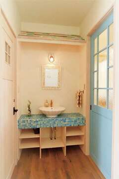 玄関をはいるとベベル板の屋根がかわいい洗面コーナーがお出迎え。ドアや引き戸も造作の1点もの。チェッカーガラスや泡のはいった歪みのあるガラスが既製品に
はない雰囲気を生み出している