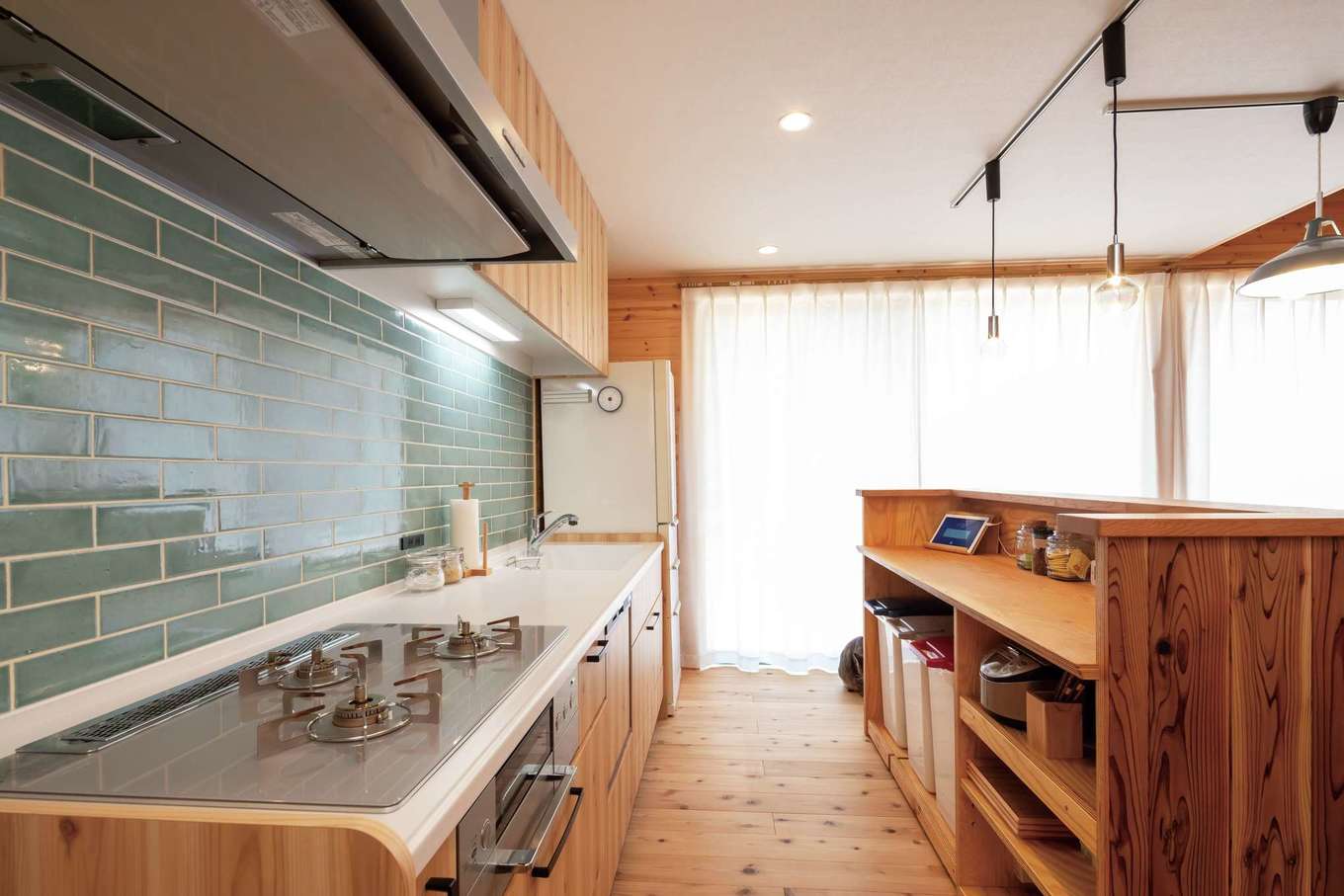 フジモクの家（富士木材）【デザイン住宅、自然素材、平屋】なるべく部屋を広く使えるようキッチンは壁付けに。アイランドの木製キャビネットは友人の手づくり。淡いブルーのタイルがアクセントに