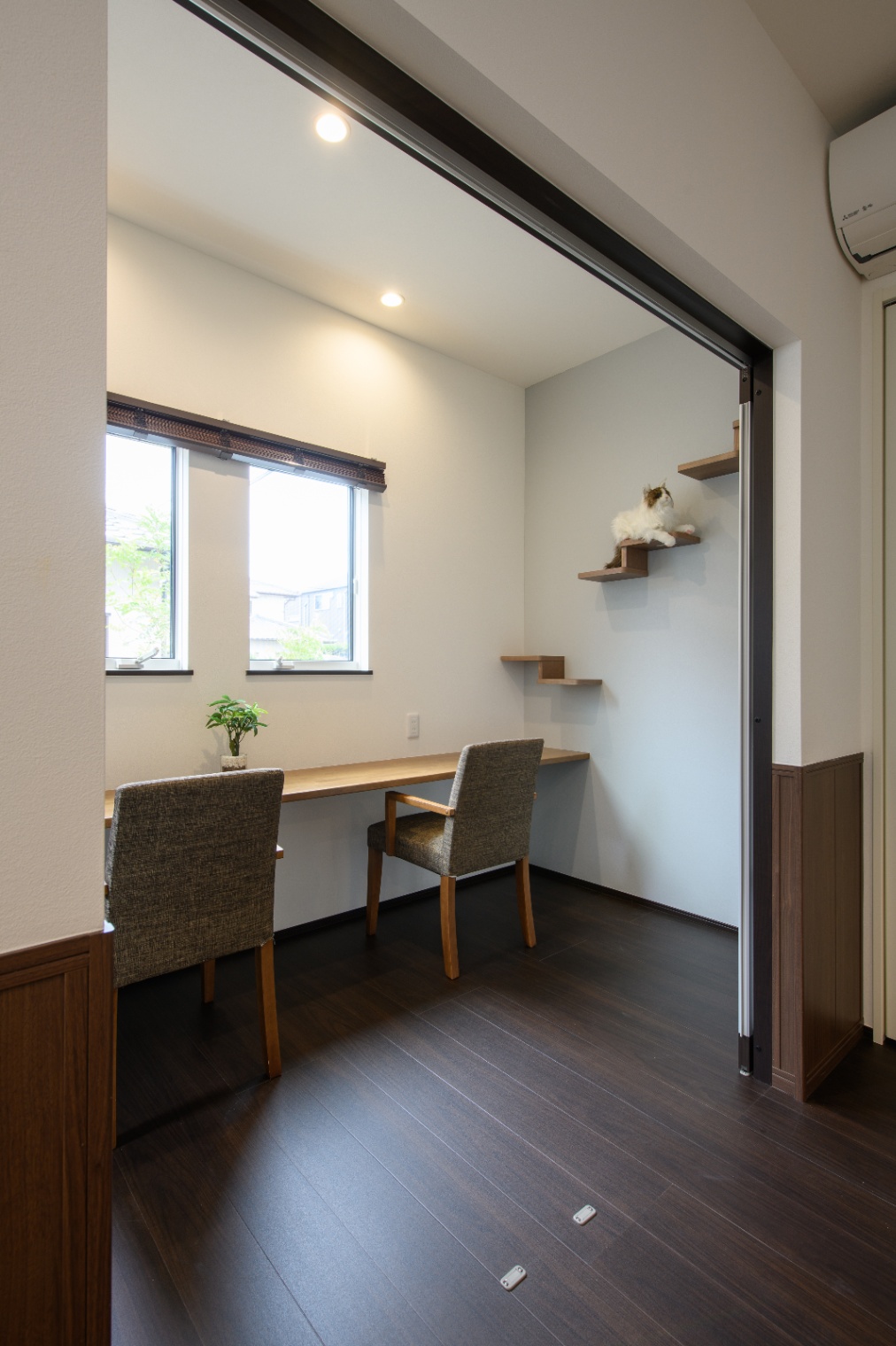 Sus∞Eco Home（サスエコホーム）｜窓から自然光が差し込む、落ち着いた雰囲気のワークスペースである。二人用のデスクが設置され、ゆったりと作業や読書ができる環境が整っている。