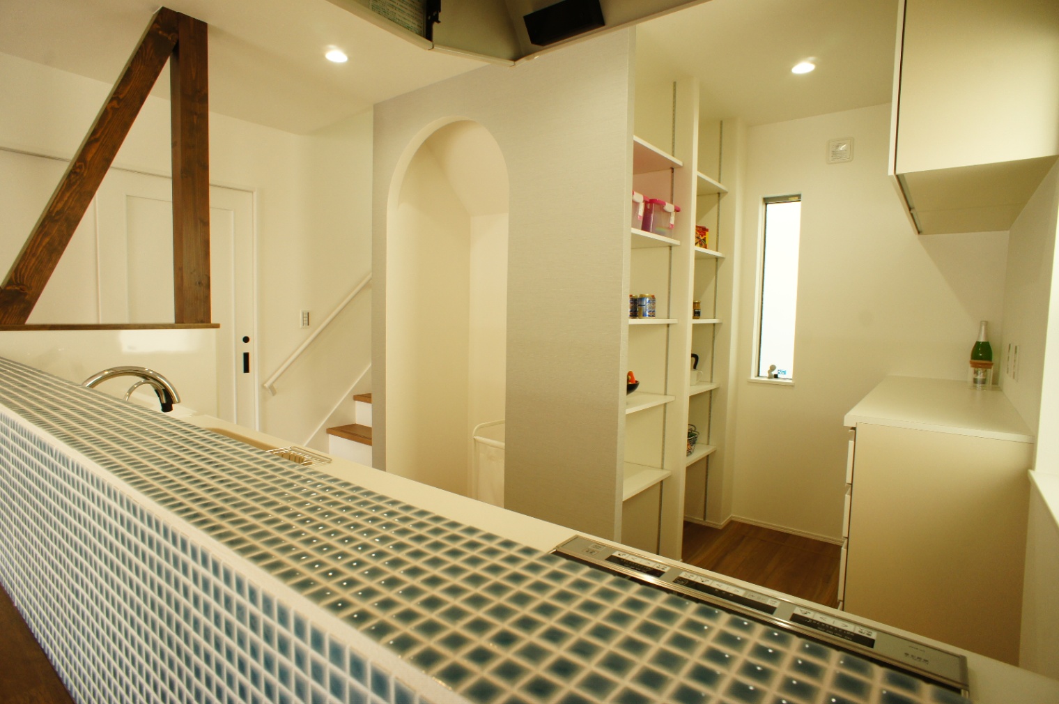 小野田産業～designers house project～｜白を基調とした明るいキッチン。タイル張りのカウンターが特徴で、奥の収納スペースには調味料やストックを整然と置くことができる。