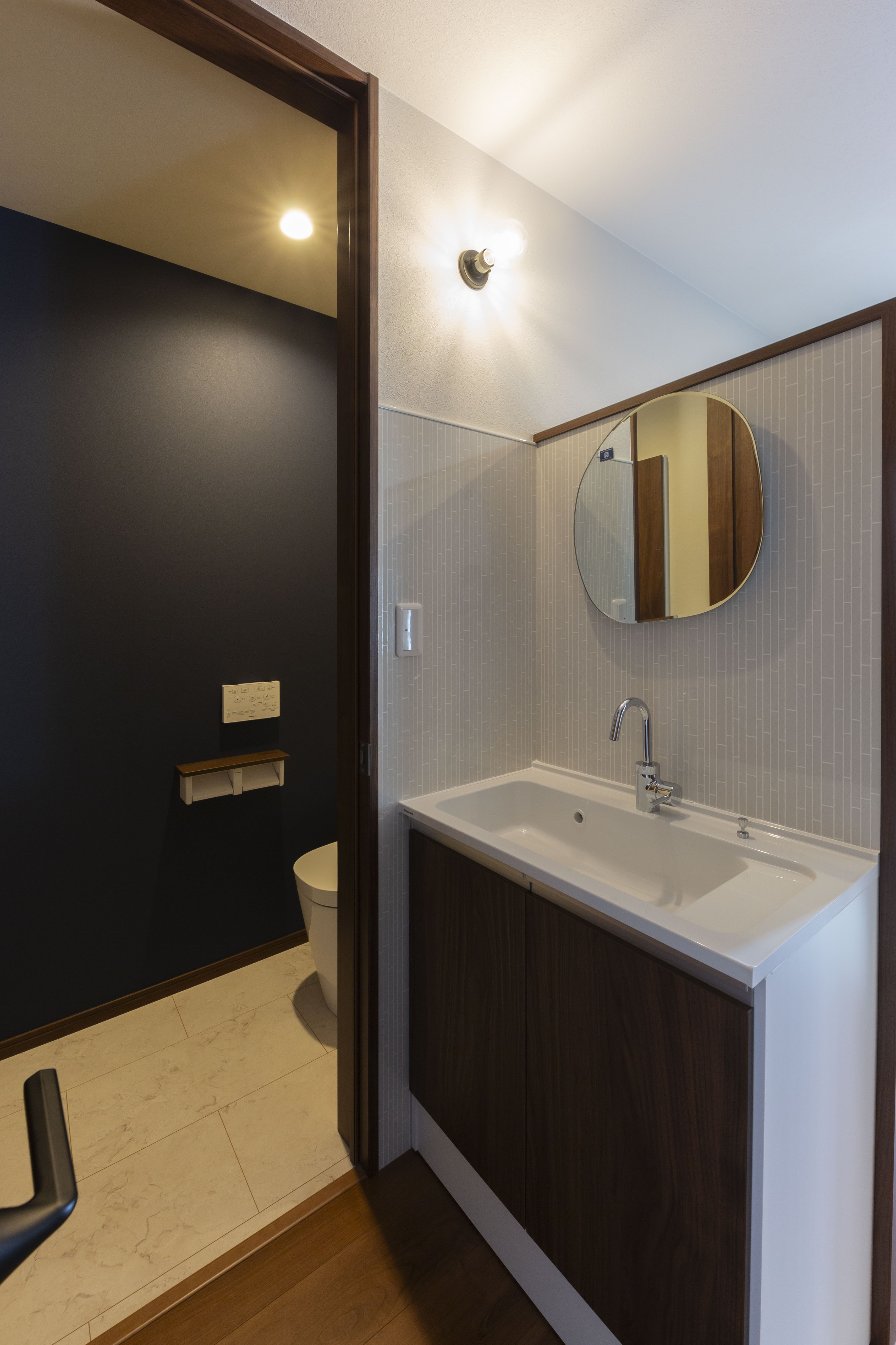 感動ハウス｜シンプルで落ち着いたデザインのトイレと洗面スペース。小さなスペースにも関わらず機能的でスタイリッシュな洗面台が隣接している。