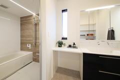 モダンで機能的な洗面スペース。シンプルなデザインと広々としたカウンターが特徴で、洗面や身支度がしやすい環境を提供。リラックスムードのバスルームと直結した配置。