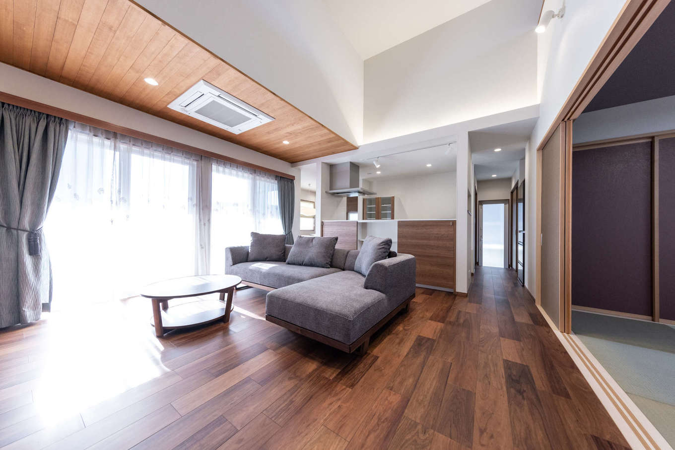 渡辺建設【デザイン住宅、夫婦で暮らす、平屋】勾配天井を活かした吹抜け感覚のLDKは24畳の広さ。天井高は最大で4.5m。同社の代名詞ともいえるテクノストラクチャー工法により実現した、大空間・大開口リビングだ。天井の一部にはレッドシダーを張って、エアコンをビルトインに