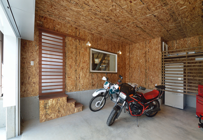 構造用合板を表しにしたビルトインガレージ。窓の先は玄関となっていて、その隣に直接出入りができるドアも設けてある