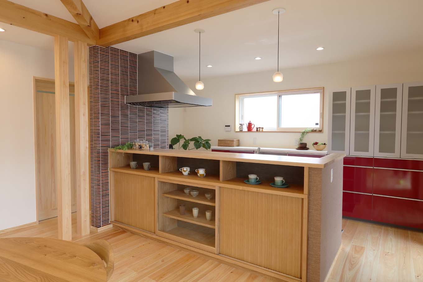 エコフィールド【自然素材、省エネ、間取り】キッチン収納も造作。窓側の赤い収納扉がアクセントに