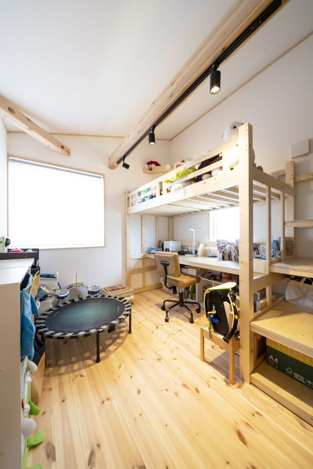明るい日差しが差し込む子ども部屋。ロフトベッドと机があり、勉強や遊びの両方に活用できる機能的なデザインである。