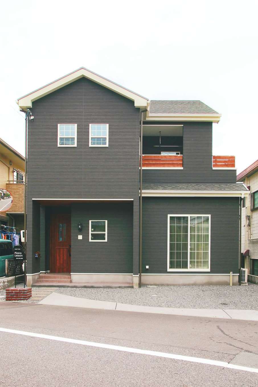 三和建設【趣味、間取り、インテリア】ダークカラーのラップサイディング調とバルコニーや玄関ドアの赤みがかった木調がマッチした外観。屋根の白いトリミングもアクセントに