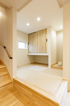 リビング横のシンプルで洗練されたデザインの小上がり空間。周囲の空間と一体化しつつも、アクセントとして独立感を出している