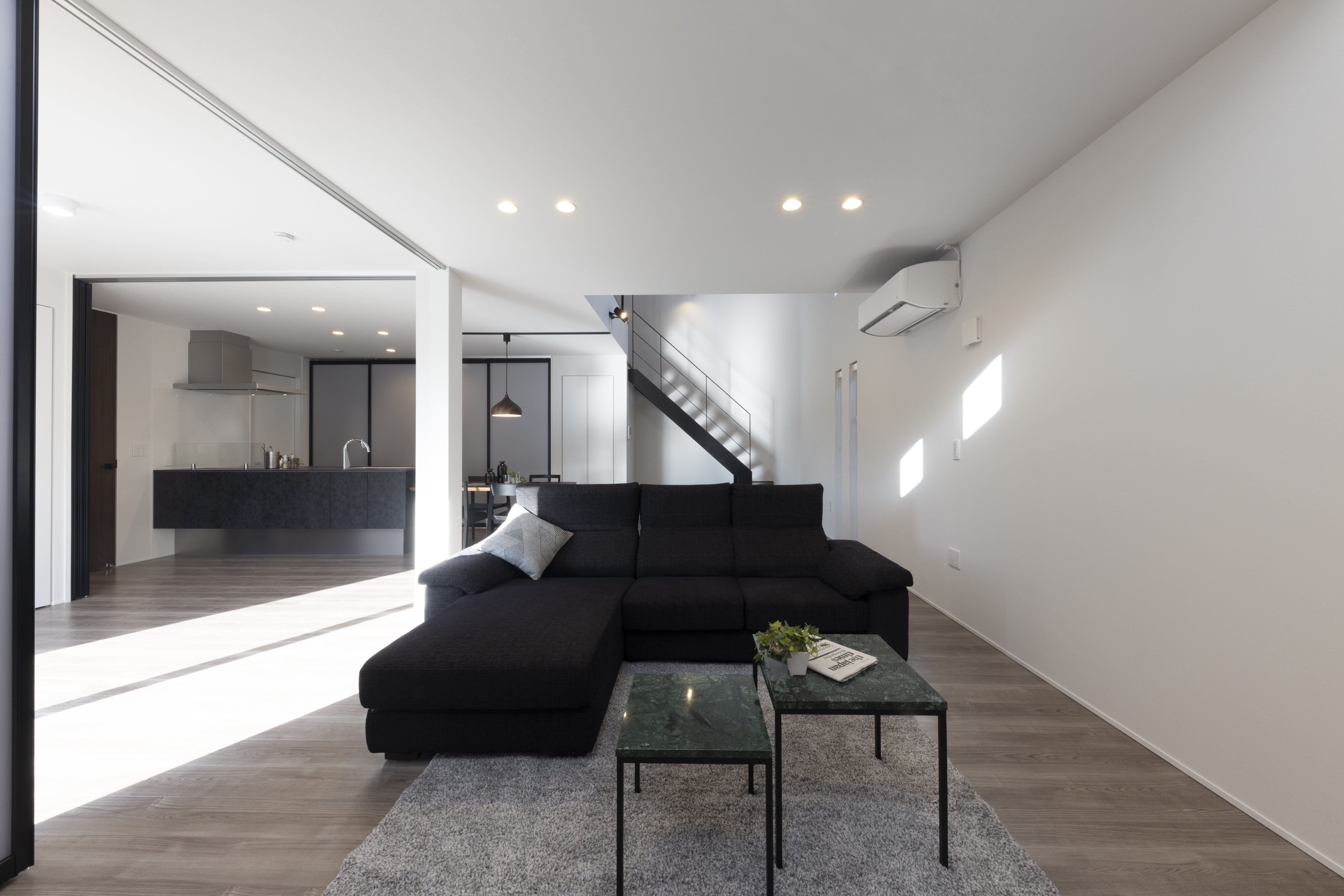 フェスティナ・レンテ｜広々としたリビングダイニングキッチンのエリア。シンプルでモダンなデザインの中に、黒のソファが映える空間。開放感があり、自然光が差し込む明るい室内。