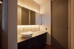 洗面所のタイルにはヘリンボーン柄を採用し、鏡の上下からは間接照明が美しく照らす。