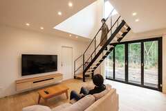 造作によるテレビボードが雰囲気にマッチ。フルオープンの窓を開ければ、木々のざわめきや小川のせせらぎが届く。ウッドデッキを設けるなど、今後は庭に手を加えていく予定