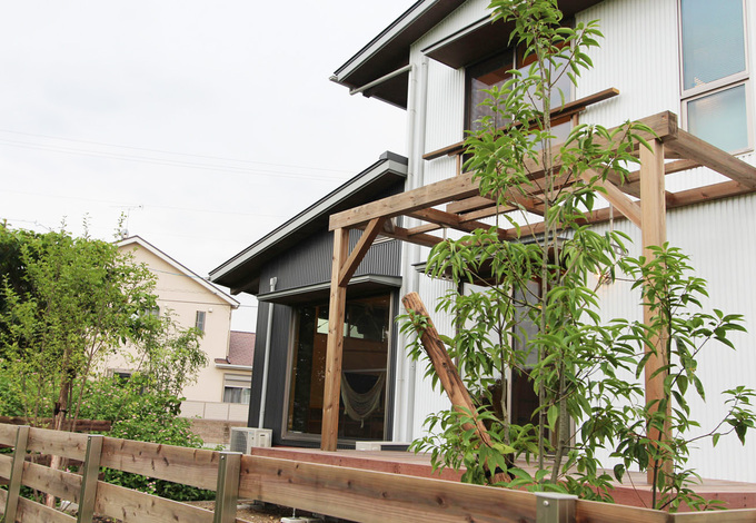 白と黒のガルバリウムで貼り分けた外観。南庭のウッドデッキ＆パーゴラは、自然に親しむアウトドアリビング