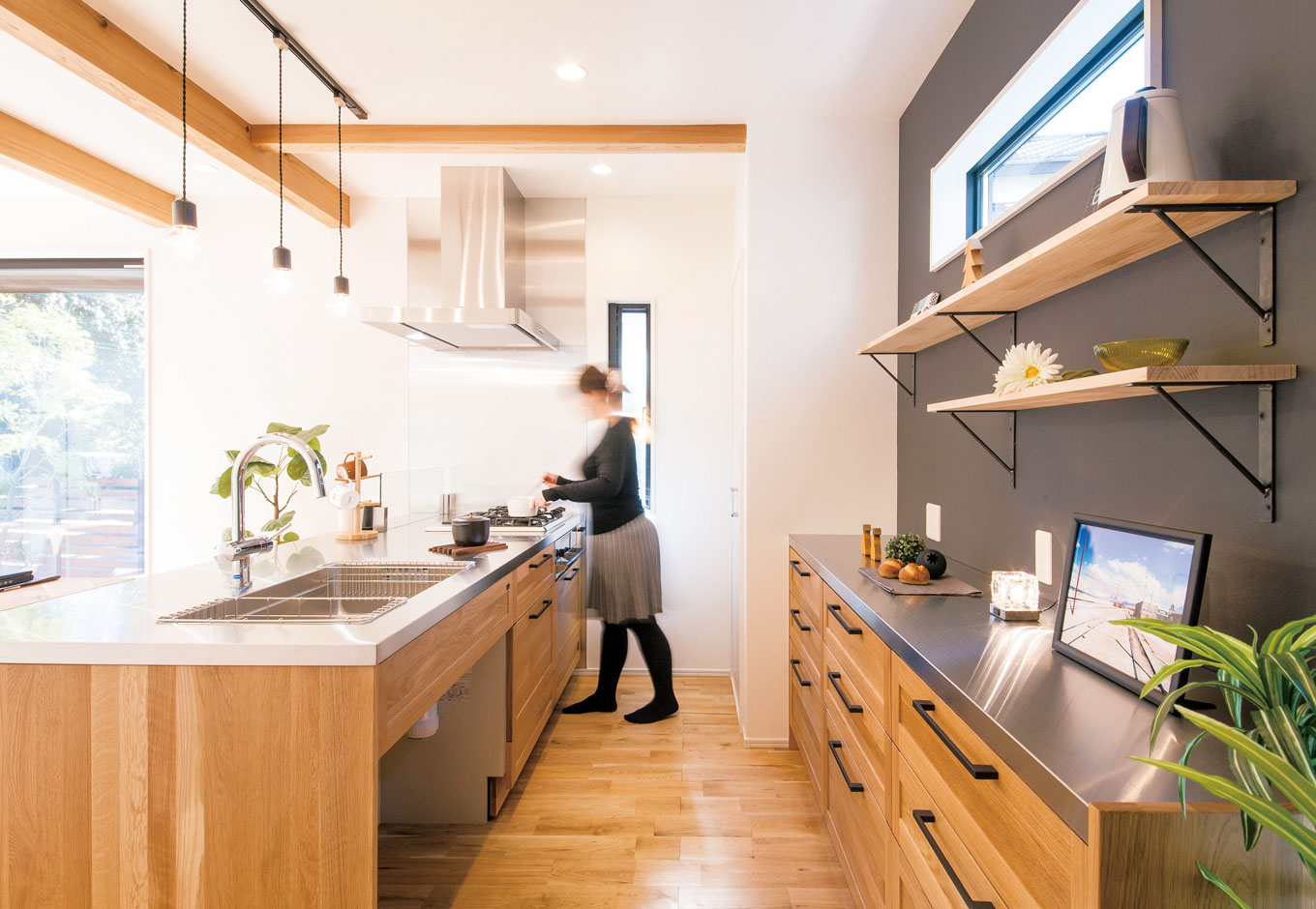 住たくeco工房【1000万円台、デザイン住宅、自然素材】キッチンと食器棚の天板はステンレスでテイストを揃えて。シンク下はくりぬいてゴミ箱の収納場所とした。食器棚も標準仕様に含まれているのがうれしい。壁はダークグレーの黒板クロスでアクセントに