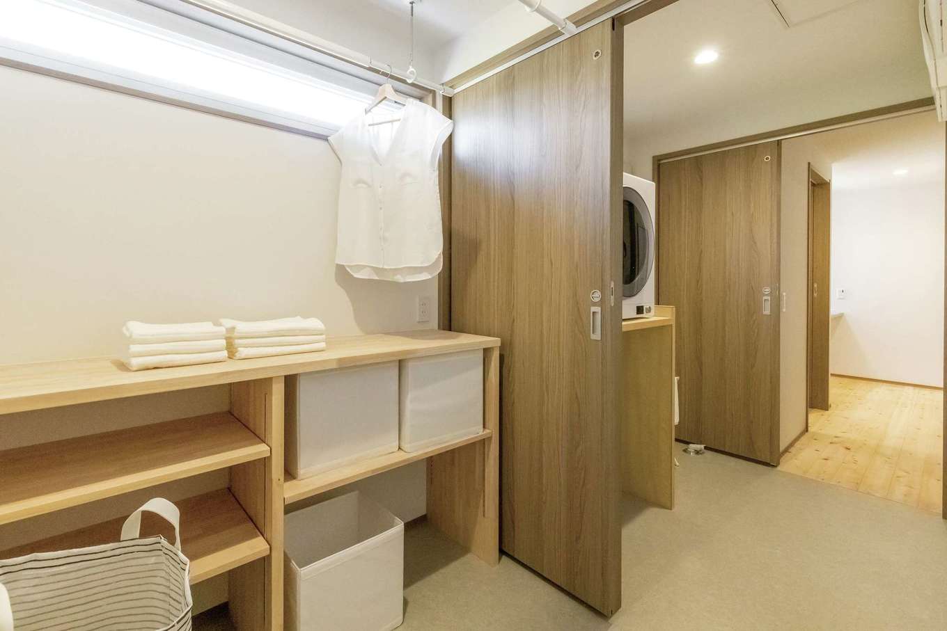 住まいるコーポレーション｜洗面室、ランドリールーム、脱衣室が一直線につながる家事ラク動線。両親の部屋からアクセスしやすい場所につくった。収納棚はすべて造作。ハイサイドライトからの光が北面でも十分な明るさを届けてくれる