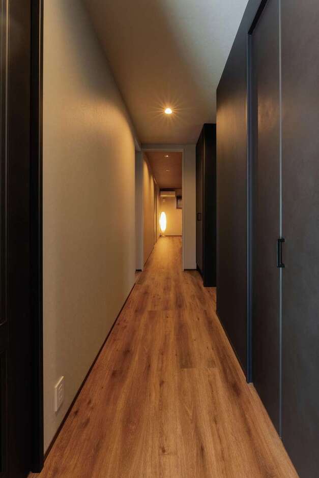 玄関の正面に真っ直ぐ伸びた廊下に沿って水回りやLDK、子ども部屋に通じるドアを配置。突き当たりは主寝室。壁や建具の一部をチャコールブラックにして、シックモダンに仕上げた