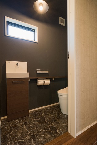 ホテル調の手洗い付きトイレ、大理石風のフロアタイルが高級感を演出