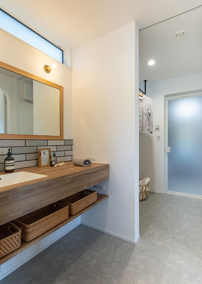 キッチンから連なる趣味室、洗面室、脱衣室の動線と、建物中央に配されたファミリークローゼットが、家事ラクに貢献する。造作の洗面台は2人が並んで使えるサイズに。タイルの目地の色まで吟味し、収納力にも配慮されている