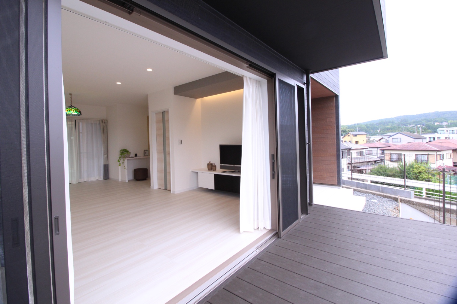 小野田産業～designers house project～｜広々としたウッドデッキがリビングとつながっており、開放感あふれる空間を演出している。室内から庭の景色を楽しめるデザイン。