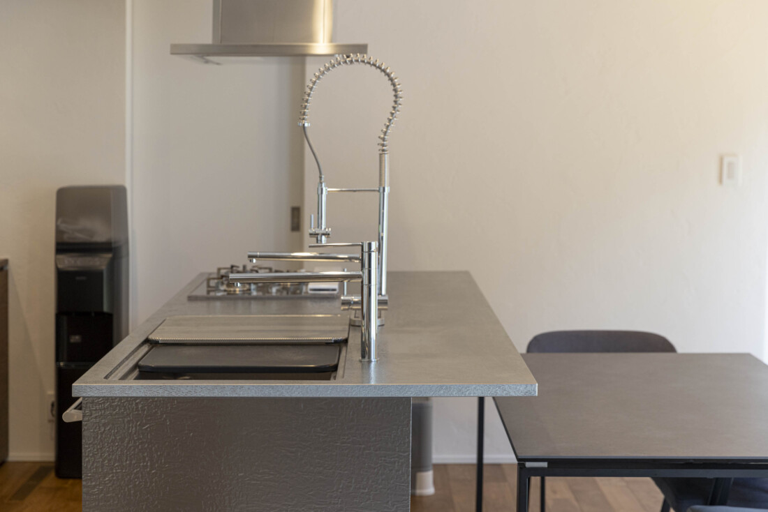 チェックハウス｜シンプルながらも機能的なデザインのキッチン。ステンレスのカウンタートップがモダンな印象を与え、調理を楽しめる空間となっている。