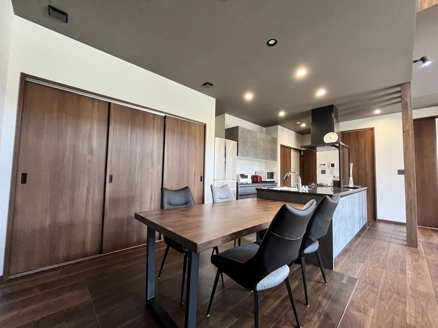 開放的なリビングダイニングキッチン。ダークウッドのテーブルとシンプルなチェアがモダンな雰囲気を演出している。