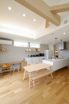 ナチュラルな木材を使用した広々としたLDK。心地よい光が差し込み、居心地の良い空間を演出している。シンプルでありながら機能的なキッチンが備わっている。