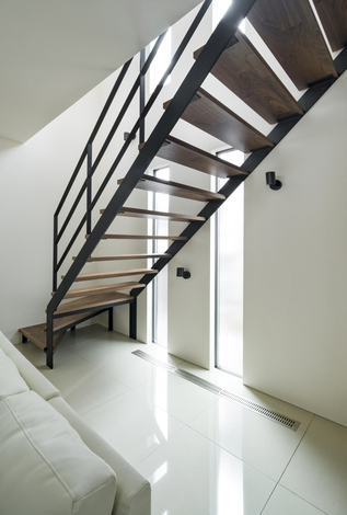 スケルトン階段は上からの日差しを１階に届ける役目も果たしている。スタイリッシュな住まいに合わせ、窓は縦スリットに。タイルの床でも全館空調のおかげで冬も暖かく快適だ