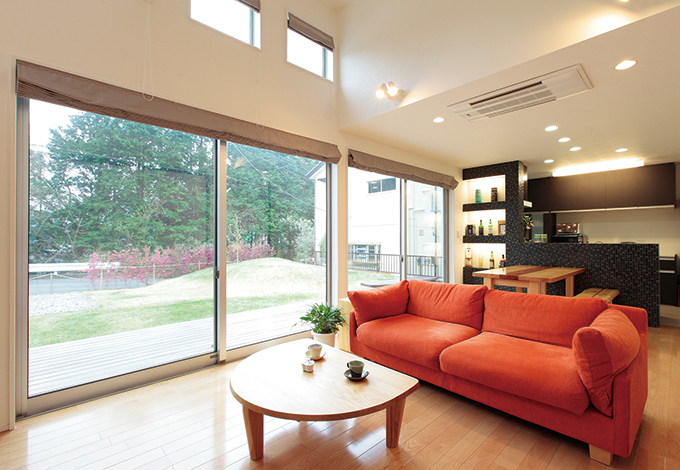 -delphi- デルフィ（藤井建築事務所） 【デザイン住宅、子育て、間取り】広い庭につながる南面は大きく開き、ウッドデッキを設けた。キッチンは黒のタイルで空間にメリハリを。ご主人の希望でウイスキーのボトルを並べる棚を造作した