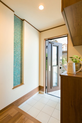 玄関ホール。ターコイズブルーのお洒落なモザイクタイルは光の加減によって色合いを変え、家族とゲストを迎えてくれる