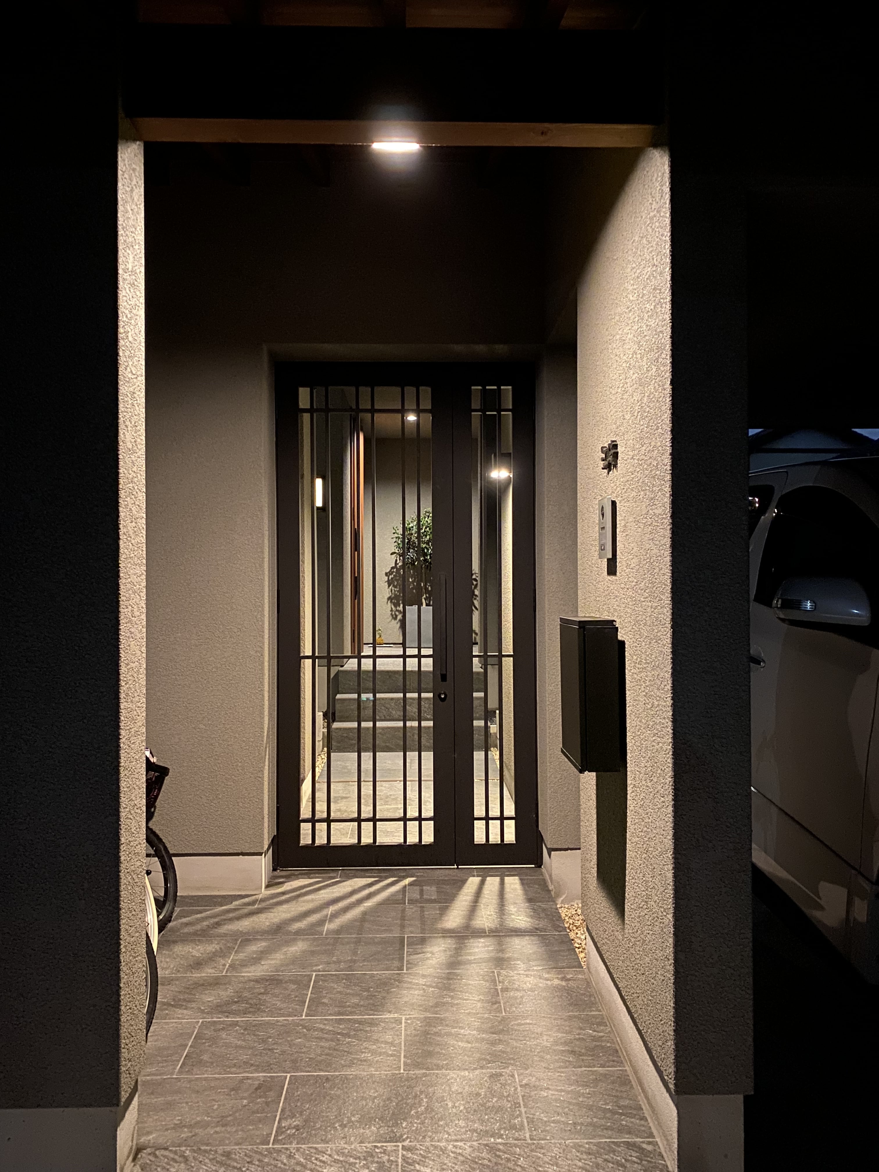 安田住宅｜安田建築設計室｜夜間に美しくライトアップされたアプローチ。シックなカラーに統一されたデザインが、訪れる人を暖かく迎え入れる雰囲気を醸し出している。