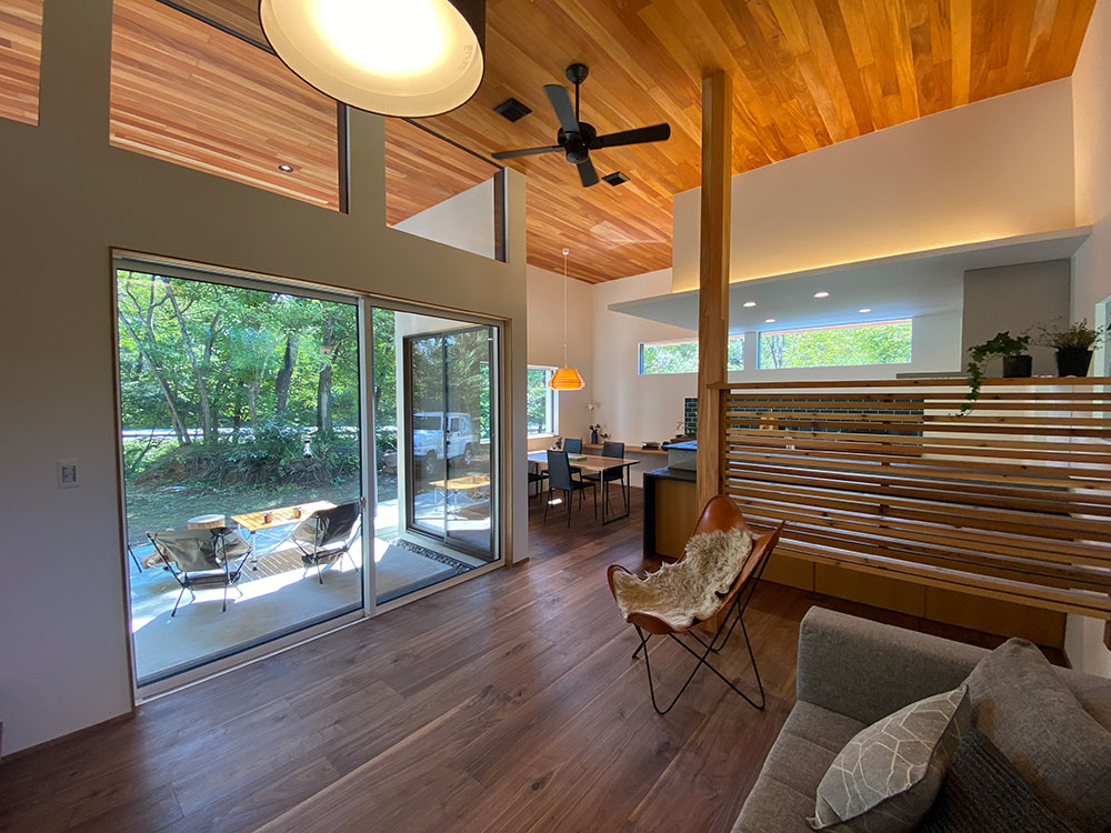 Techno Home Aizawa【デザイン住宅、自然素材、高級住宅】大開口の明るいLDK。外と繋がるデッキがより開放感を生み出す。リビングどダイニングの間には、飾り棚にもなるレッドシダーの仕切りを配置