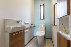 水色のアクセントクロスが清々しいトイレ。両サイドの壁面に収納スペースを確保