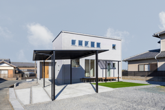 グレーの塗り壁で仕上げた落ち着いた外観。カーポートに人工芝、テラス屋根つきのウッドデッキと外構にも拘わりました。