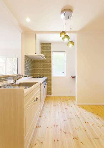 グリーンのタイルが美しいキッチン。炎で調理したい派の奥さまはガスをチョイス