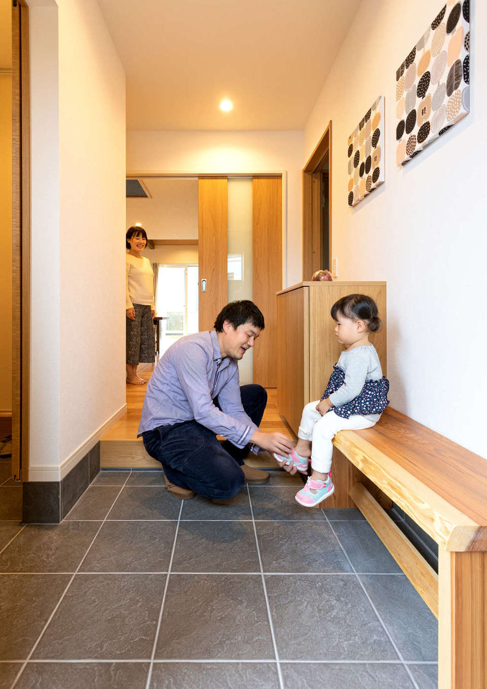 Yamaguchi Design 【省エネ、間取り、平屋】土間仕上げの玄関ホール。大工さん手づくりの木のベンチは、子どもも祖母も靴を履きやすくて大助かり。左側に家族専用のシューズクロークを設け、玄関は常にスッキリと