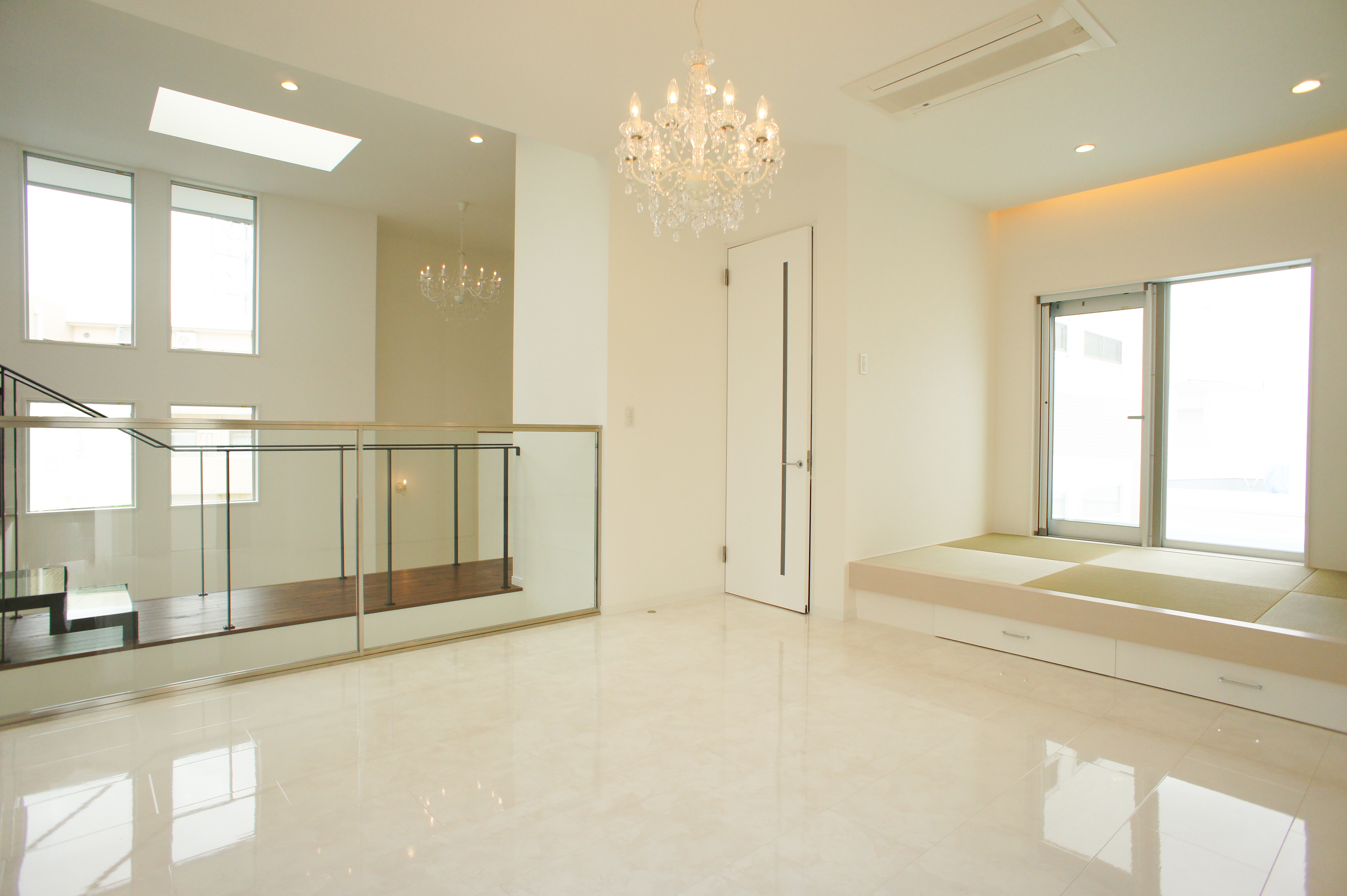 小野田産業～designers house project～｜明るくモダンな和洋折衷の畳スペース。大きな窓から自然光が降り注ぎ、リラックスできる空間を演出する。階段とシャンデリアが調和し高級感を感じさせるデザイン。