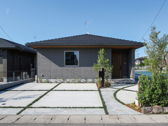 シンプルでモダンなデザインの平屋の外観。手入れの行き届いた庭と駐車スペースがある。